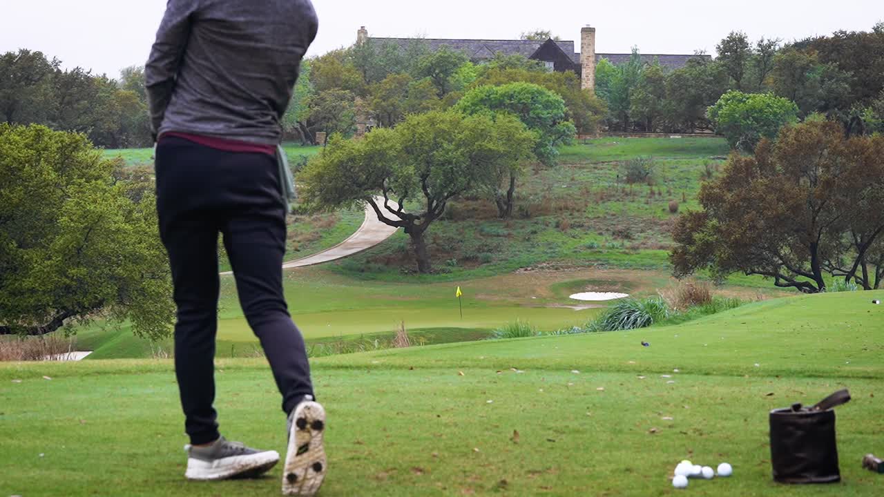 안개 낀 날 파 3 골프 코스에서 연습하는 홀 옆에 있는 핀에 가까운 골퍼가 샷을 천천히 밀어 넣습니다.