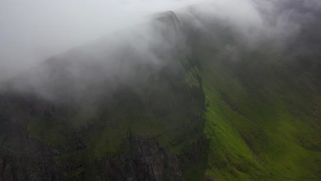 Nubes-Brumosas-Sobre-Un-Precipicio-Empinado-En-La-Cima-De-Un-Acantilado-En-Las-Islas-Feroe,-Vista-Aérea