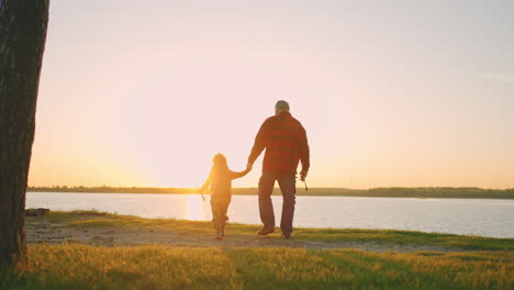 Wandern-Zum-Fluss-Der-Kleine-Junge-Und-Sein-Großvater-Gehen-Zur-Küste,-Um-Bei-Sonnenuntergang-In-Der-Natur-Zu-Angeln