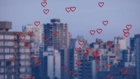 animation of multiple red heart icons floating against aerial view of tall buildings