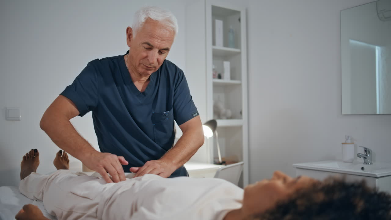 practicante tocando el estómago de una mujer en la sala del hospital. médico masajeando al paciente