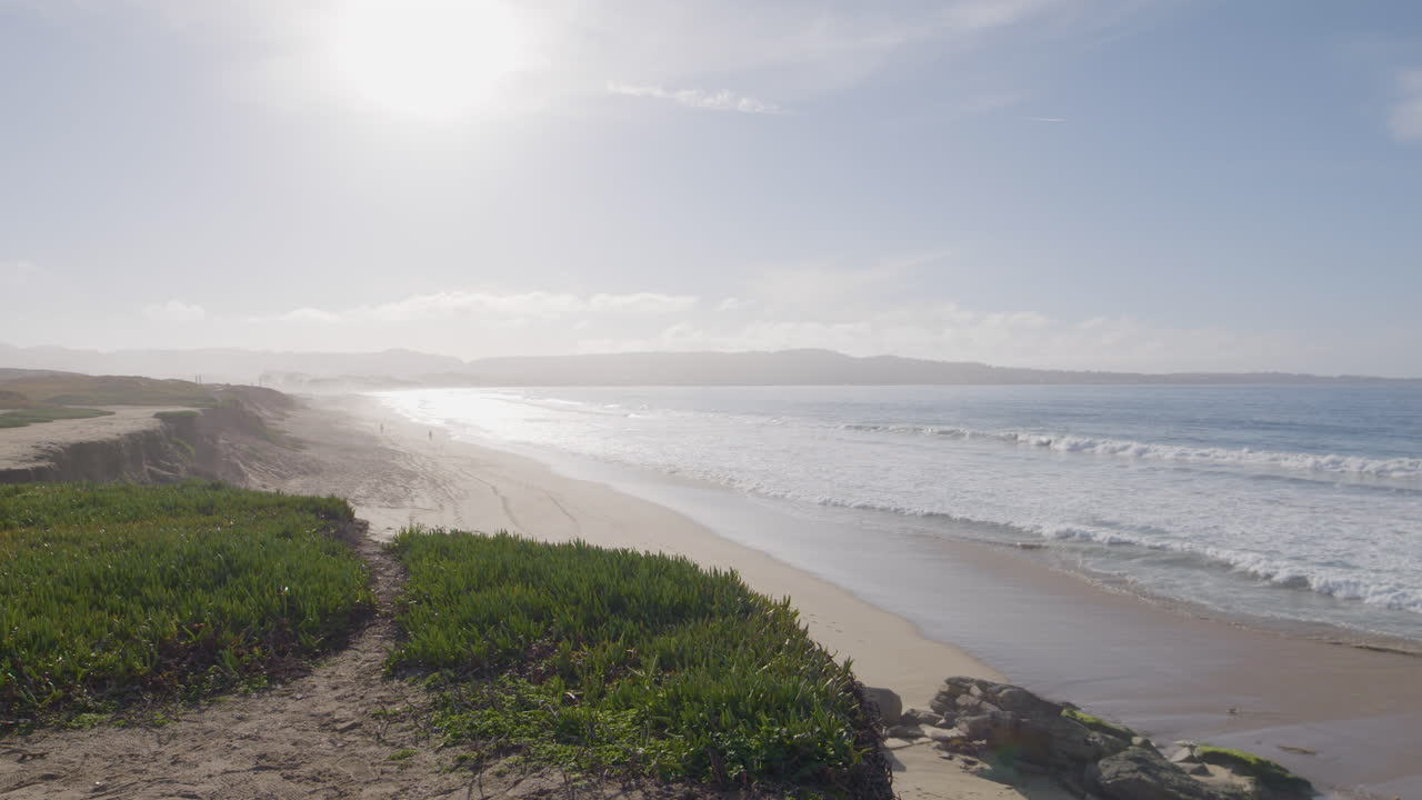 toma panorámica en cámara lenta de un día soleado en marina state beach monterey bay california con ondulantes olas del océano en una playa de arena