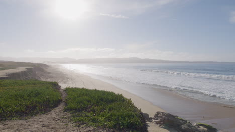 toma panorámica en cámara lenta de un día soleado en marina state beach monterey bay california con ondulantes olas del océano en una playa de arena