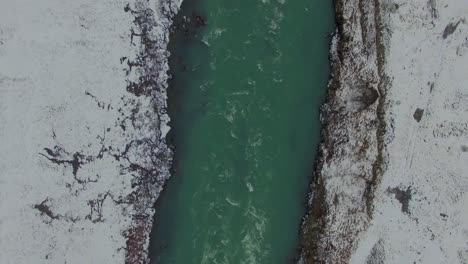 iceland in winter snowy river from overhead slow scroll down drone 4k