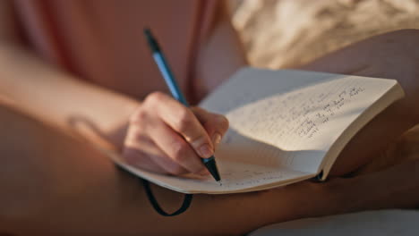 hands writing personal journal in sunlight closeup. calm girl rest morning bed