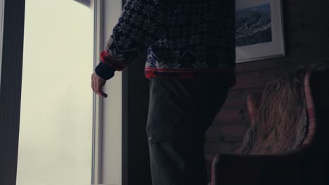 겨울 옷을 입은 남자가 도착하여 집에 있는 소파에 앉는다