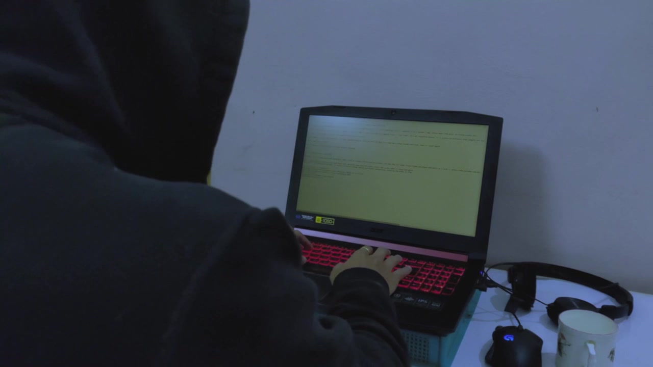 En hacker-koder arbejder og taster på en bærbar computer.