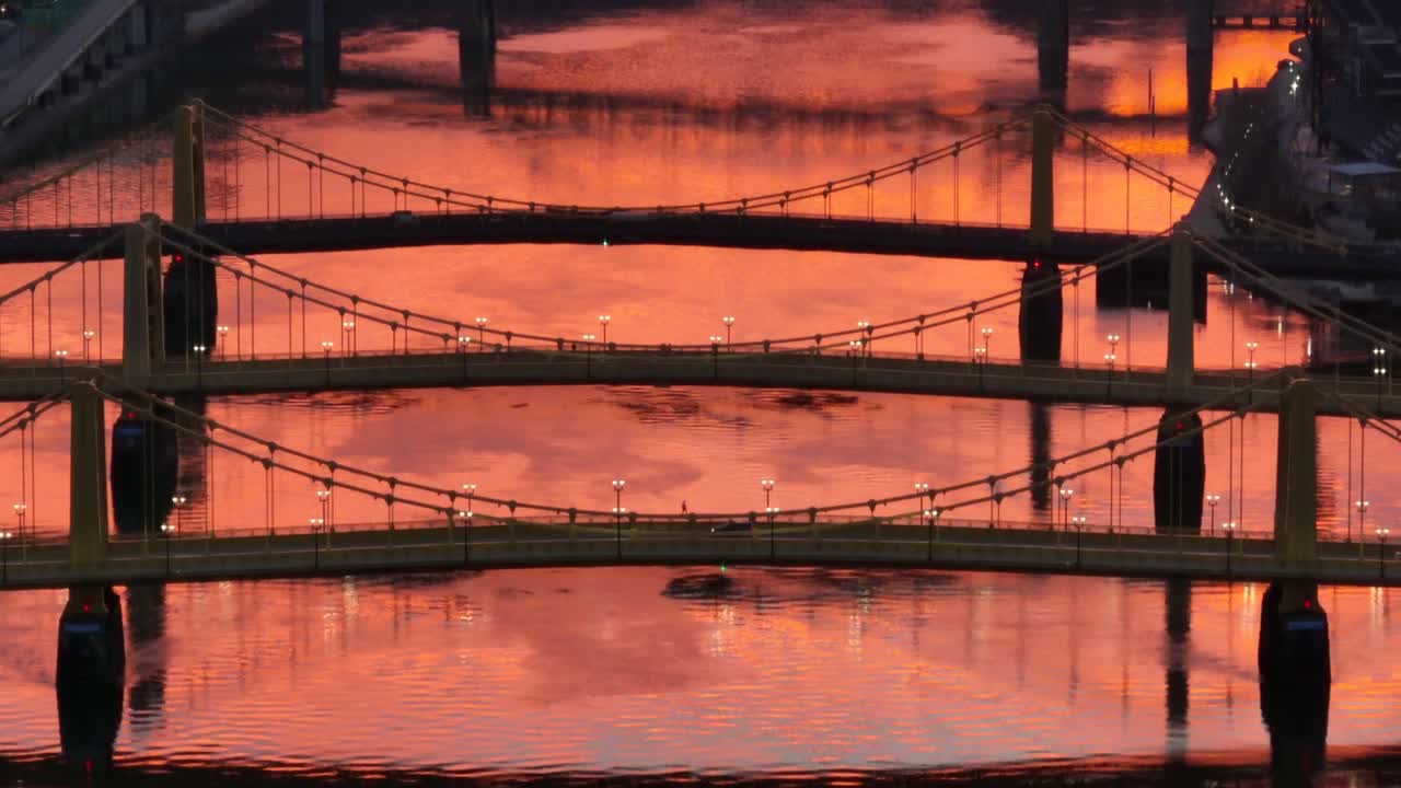 앨러게니 강에서 주황색 일몰을 반사하는 동안 로베르토 클레멘테, 앤디 워홀, 레이첼 카슨 다리