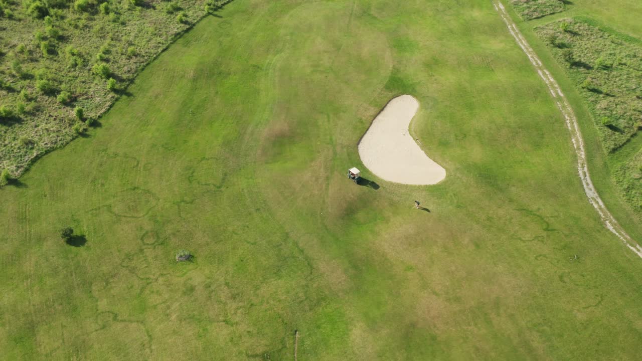 한 남자 가 시골 지역 에 있는 그린 코스 에서 카트 근처 에서 골프 를 치고 있다