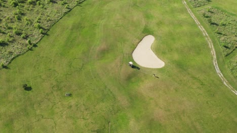 man plays golf near cart on green course at rural site