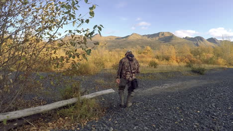 un fotógrafo de naturaleza y vida silvestre se sienta cerca de un río de salmón durante una sesión de fotos de otoño en el desierto de la isla de kodiak, alaska