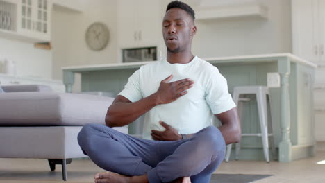 Focused-african-american-man-practising-yoga-meditation-in-sunny-living-room,-slow-motion