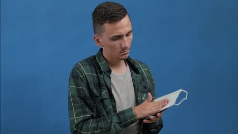 el hombre se sienta, usa el teléfono, luego limpia su pantalla con una máscara médica y la desecha.