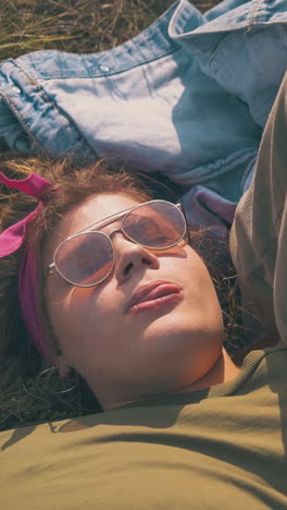 overweight girl in glasses and tipsy partner rest after day hike on green grass at camp in calm autumn evening closeup