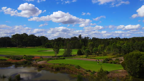 Male-golfers-teeing-off-onto-golf-course-fairway-under-beautiful-blue-sky