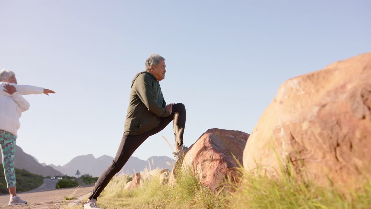 파란 하늘을 가진 산에서 느린 움직임으로  ⁇ 어 나가는 행복한 고령 미인 부부