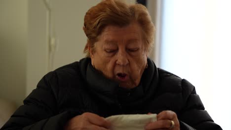 elderly woman wiping nose with tissue at nursing home