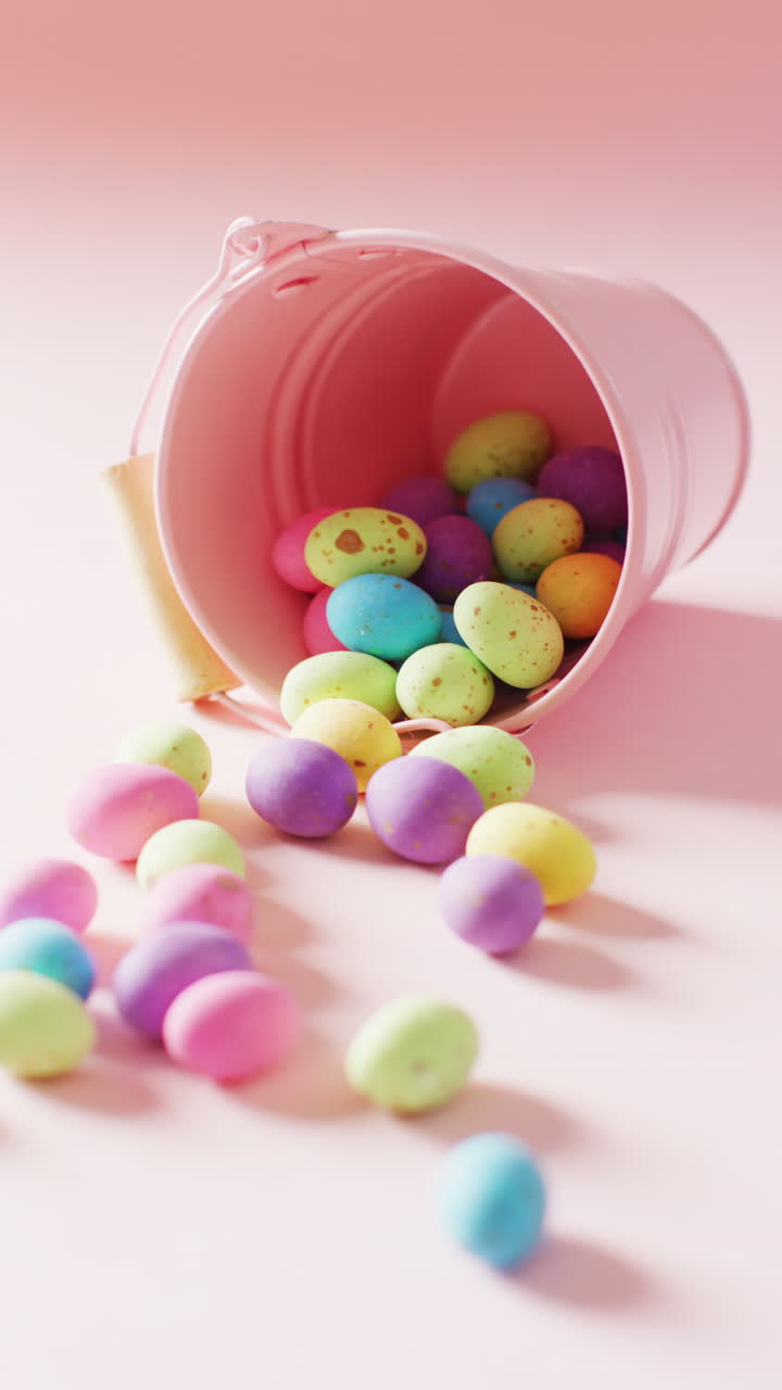 Vertical video of bucket with colorful easter eggs on pink background with copy space