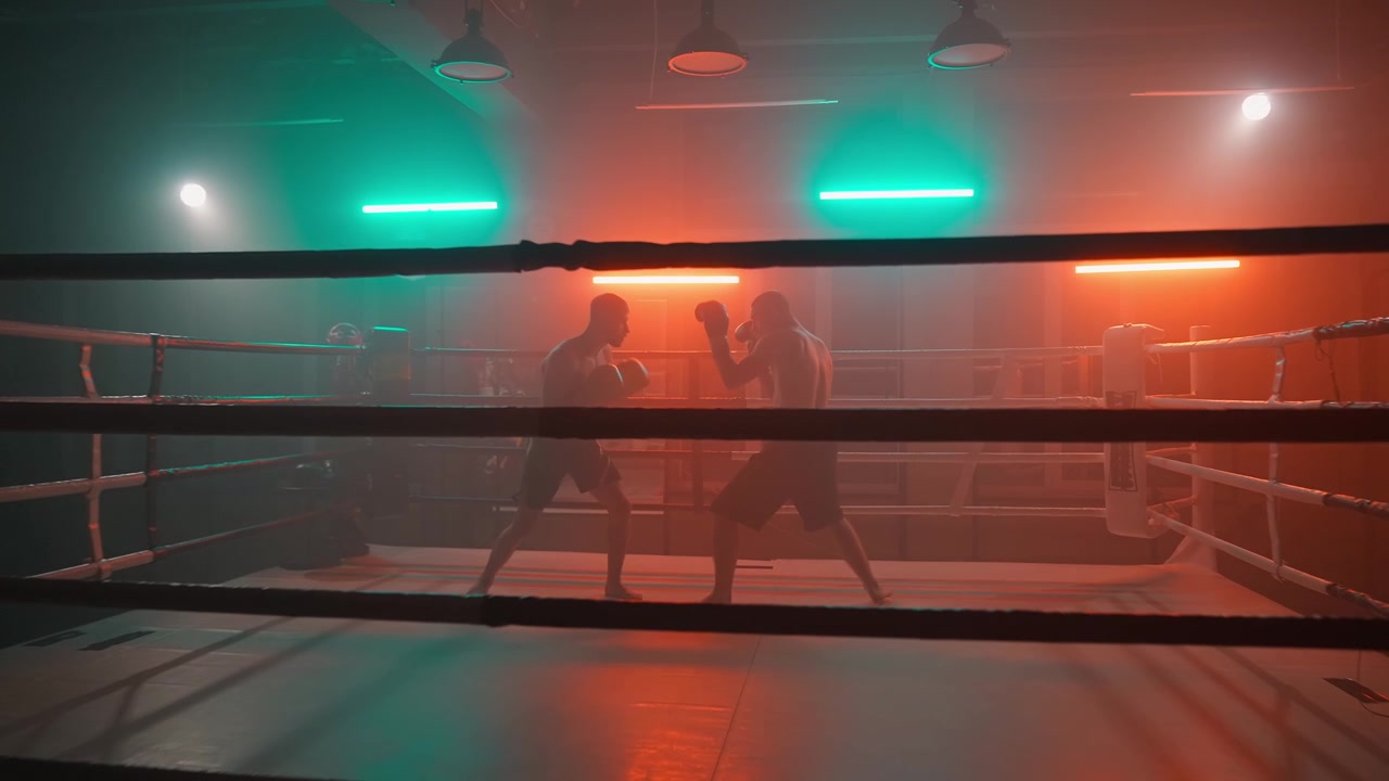 Männliche Boxer trainieren im Boxring mit dramatischer Neonbeleuchtung