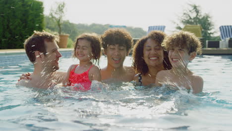 Retrato-De-Una-Familia-Multirracial-Relajándose-En-La-Piscina-Durante-Las-Vacaciones-De-Verano-Juntos