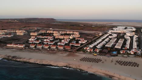 aerial view of bikini beach parasols with resort and villas during sunset light