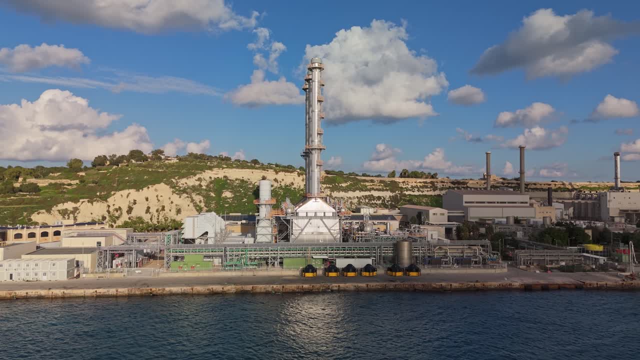 Marsaxlokk, Malta'daki Delimara enerji santralinin endüstriyel yapılarını, bacalarını ve berrak bir kış gökyüzüne karşı kıyı çevresini vurgulayan yandan, havadan görünümü