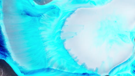pouring of white ink in blue liquid medium forming shimmering galaxy