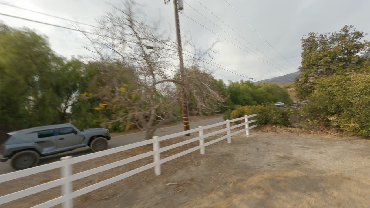 vista lateral fpv de un hermoso coche todoterreno conduciendo por un pueblo callejero