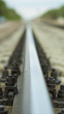 una vista de cerca de una vía ferroviaria que se extiende en la distancia, el video se centra en el ferrocarril y sus fijaciones, con el fondo hermosamente borroso
