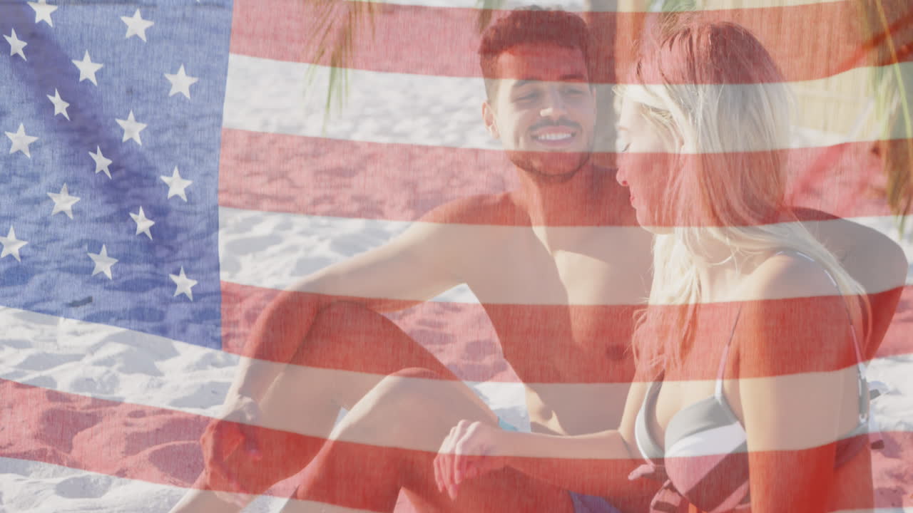 animación de la bandera estadounidense ondeando sobre una pareja sonriente enamorada en la playa