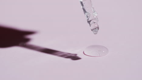 Video-of-make-up-pipette-and-drops-of-serum-with-copy-space-on-pink-background