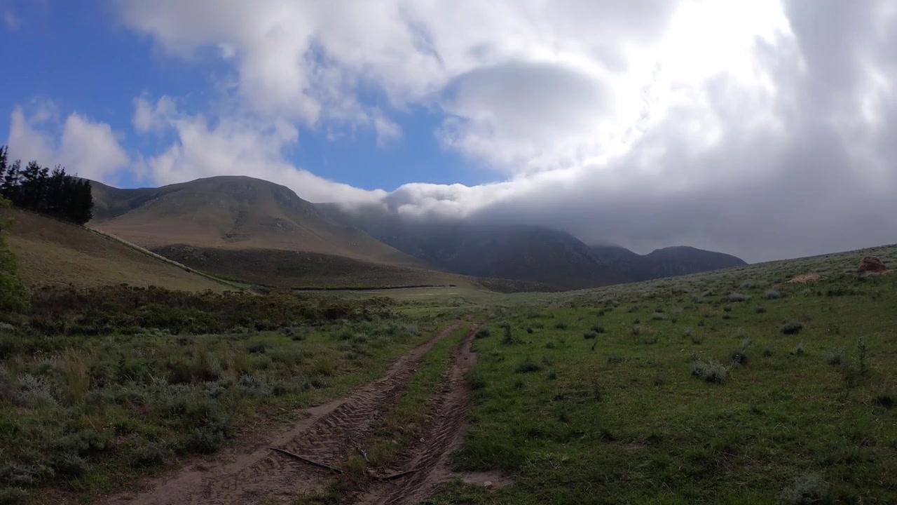 Hyperlapse 4K di nuvole che si muovono sopra la montagna. Nebbia oceanica e luce solare che filtra attraverso la nebbia e le nuvole. Campagna agricola in Sudafrica. Hermanus, Capo Occidentale. Estate. Vita di campagna. Natura pacifica.