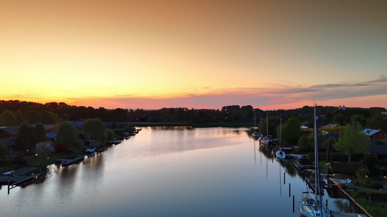 Rising over the waterscape with the boats at the banks. Amazing pink orange sky above the scenery at sunset. Aerial view.