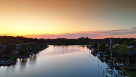 rising over the waterscape with the boats at the banks. amazing pink orange sky above the scenery at sunset. aerial view.