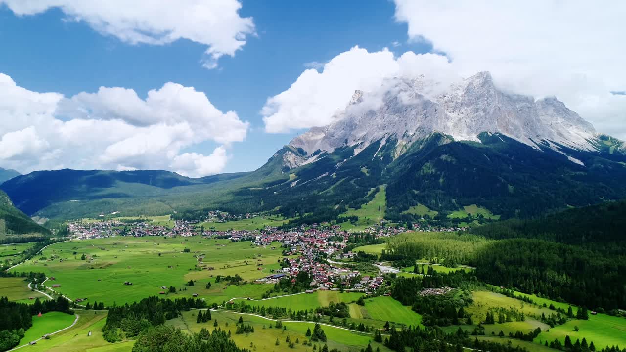 Aerial pan reveals colorful alpine village nestled between green Swiss hills