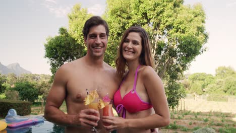 feliz pareja caucásica bebiendo cócteles durante un día soleado