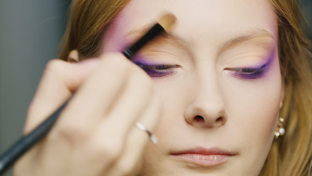 una joven mujer de ojos azules se maquilla en la cara