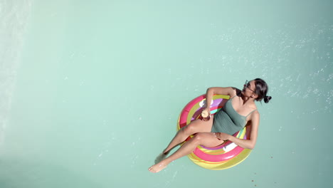 relaxing in pool, woman on inflatable ring enjoying drink in swimsuit, copy space