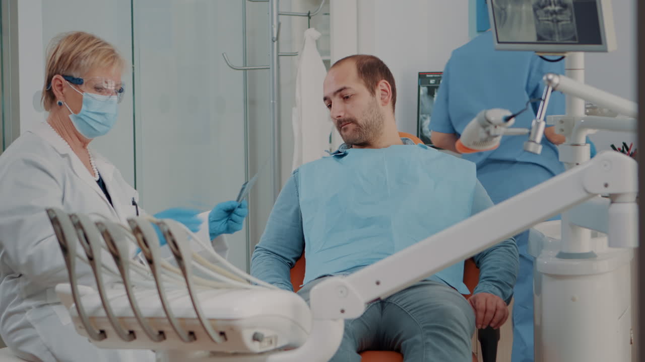 Stomatologist showing x ray scan diagnosis to patient