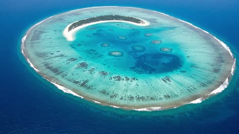 aerial view of a stunning coral atoll surrounded by turquoise waters and featuring unique geometric patterns in the sandy shoreline and vibrant marine life below