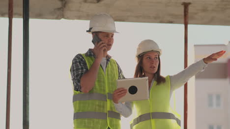 Edificio-En-Construcción-Con-Una-Mujer-Y-Un-Hombre-Constructores-Ingenieros-Constructores-Caminando-A-Lo-Largo-De-él