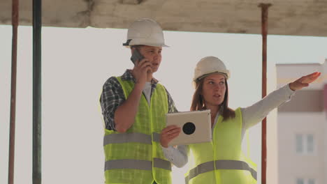 en la construcción con una mujer y un hombre constructores constructores ingenieros caminando a lo largo de él