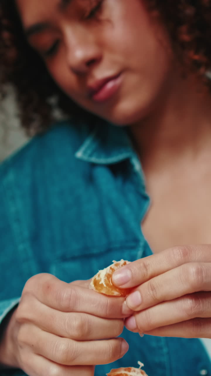 Primo piano di una donna che sbuccia e mangia un mandarino fresco