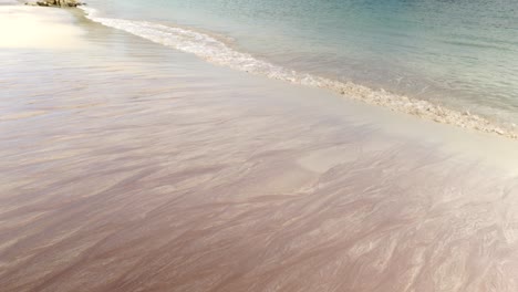 crystal clear waves gently lap against sand on a remote scottish beach on handa island as the camera tilts to reveal green cliffs and the beautiful turquoise waters of the west coast atlantic ocean