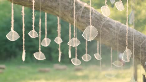 creative installation of pieces of glass hanging on a tree against a sunset background, glitters beautifully