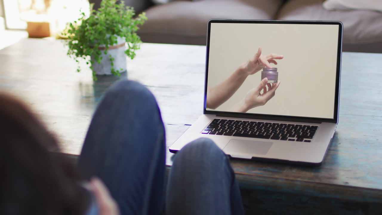 Donna al tavolo che usa il laptop, acquisti online di prodotti di bellezza, slow motion