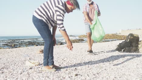 una pareja afroamericana de alto nivel limpiando la playa, cámara lenta