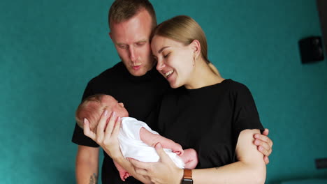 happy caucasian parents look at their newborn baby with adoration. couple smiling and talking to their beloved baby.