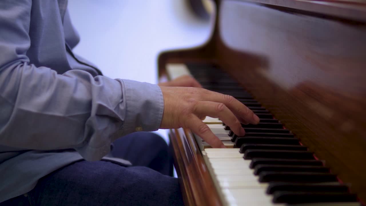 el talentoso anciano pianista músico está tocando música clásica con pantalones azul y jeans cerca de las manos moody escena cinematográfica a cámara lenta