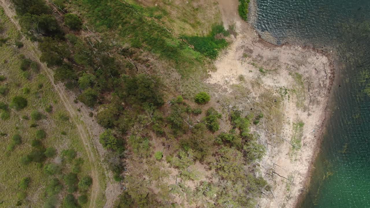 Flyover vertically of bush land and Lake foreshore ,shimmering water